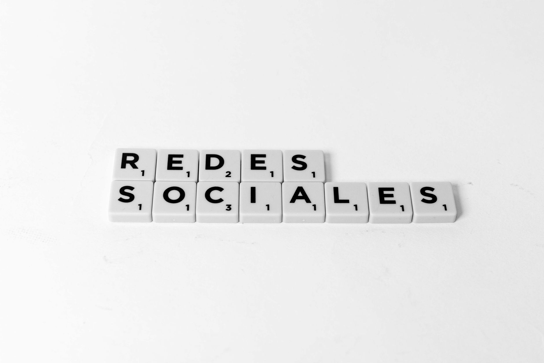 Scrabble tiles form 'Redes Sociales' on a white background, symbolizing social networks.