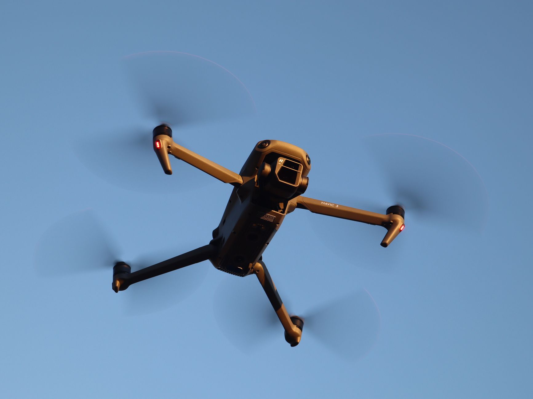 Close-up of a drone flying in a clear blue sky, highlighting its technology and mobility.