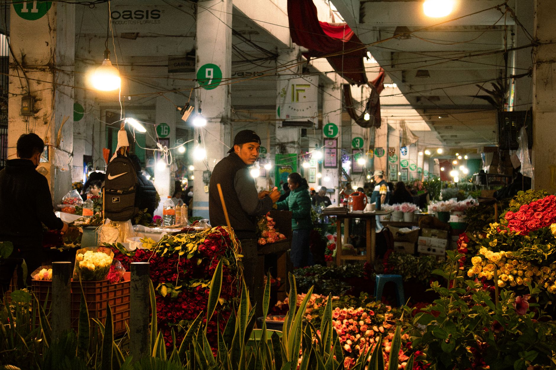 A vibrant indoor flower market in Mexico City bustling with activity and colorful blooms.