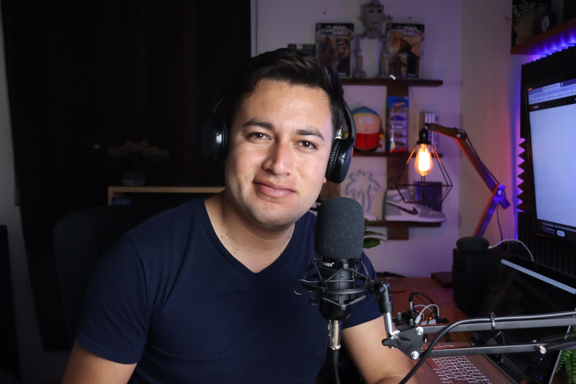 Portrait of a man in a podcast studio with headphones and microphone.